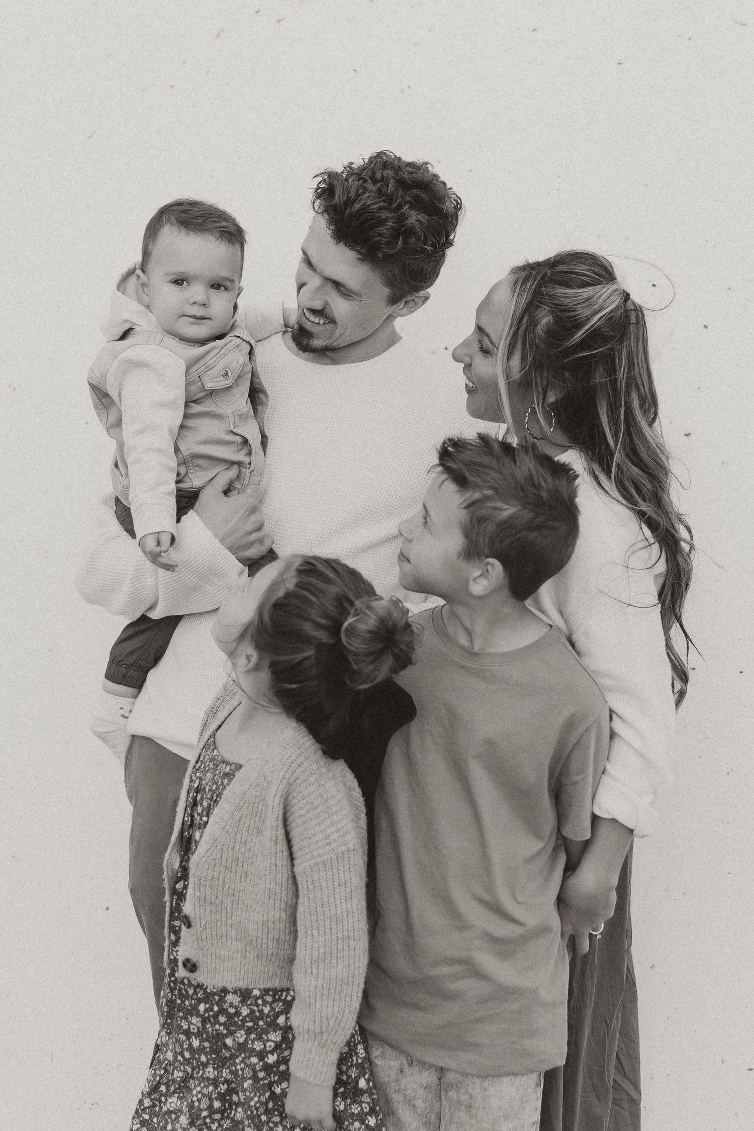 Black and white family portrait showing tender moments between parents and baby.