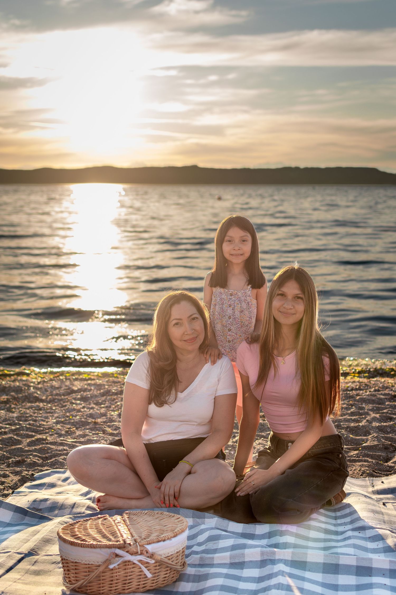 Family sitting on picnic blanket during golden hour beach mini session in Des Moines, WA