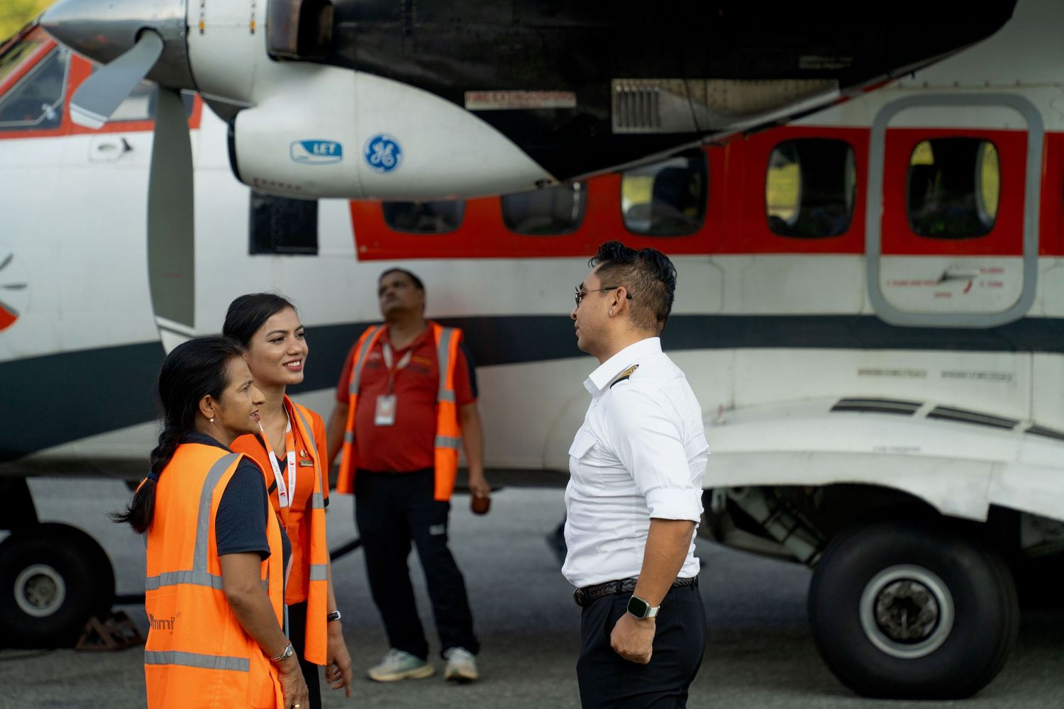 Ground crew and passengers near small aircraft on tarmac preparing for boarding.