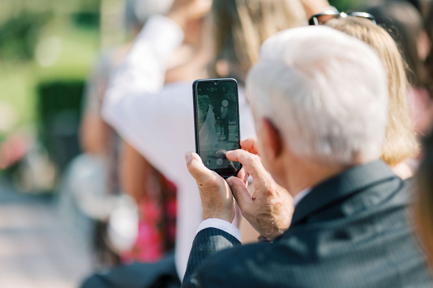 A series of people taking photos or videos with their smartphones in an outdoor setting.