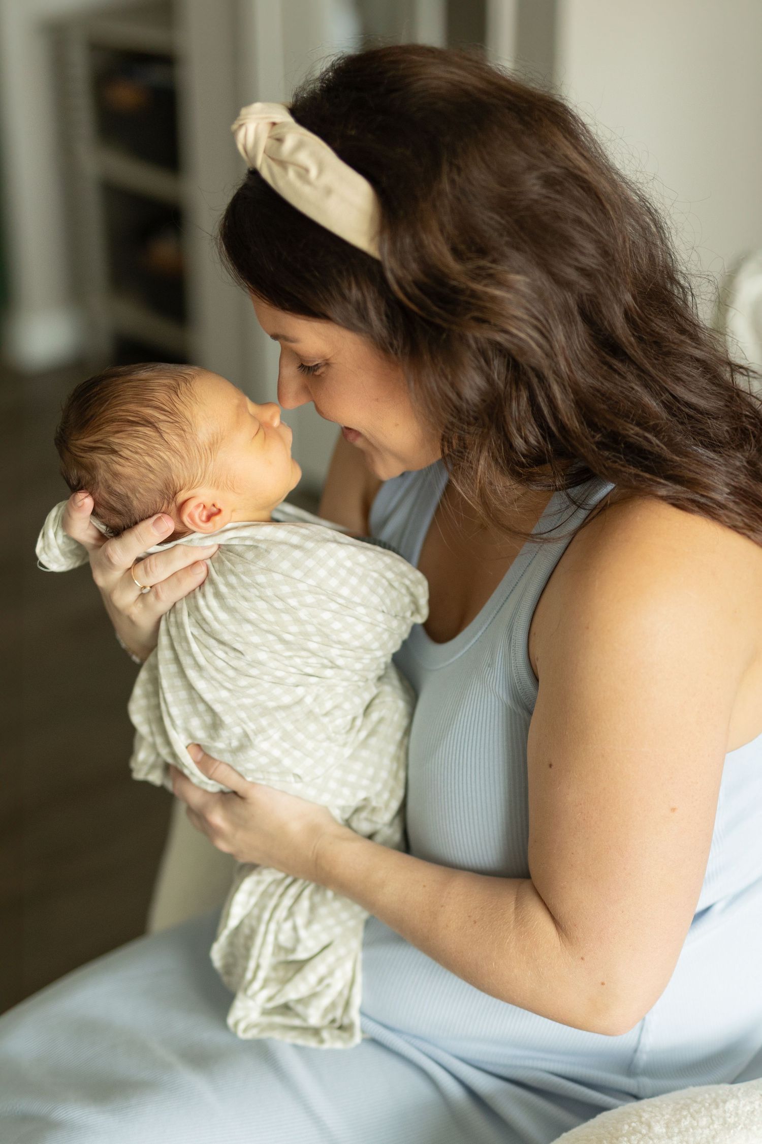 Side profile of a mother holding her newborn baby boy up to her nose