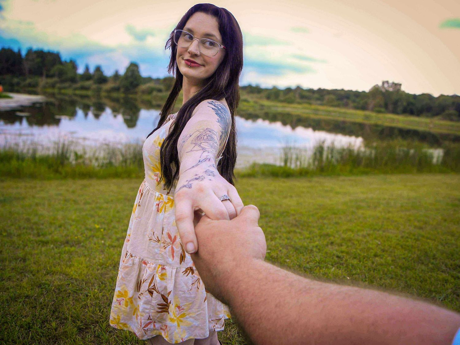 Romantic follow-me shot in a floral dress by a lake during golden hour.