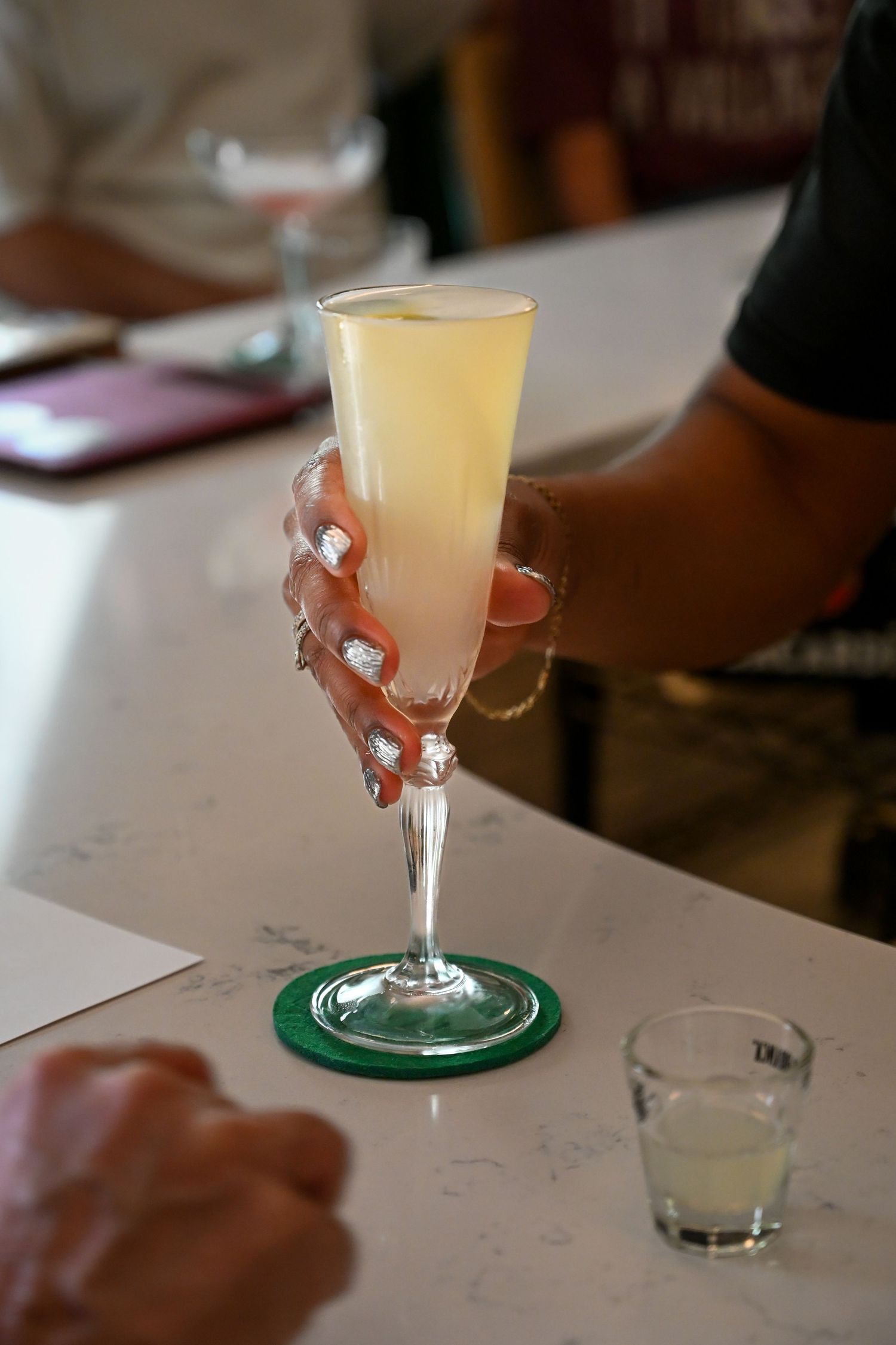 A social club happy hour invitation showing two champagne flutes toasting against a green backdrop with event details.