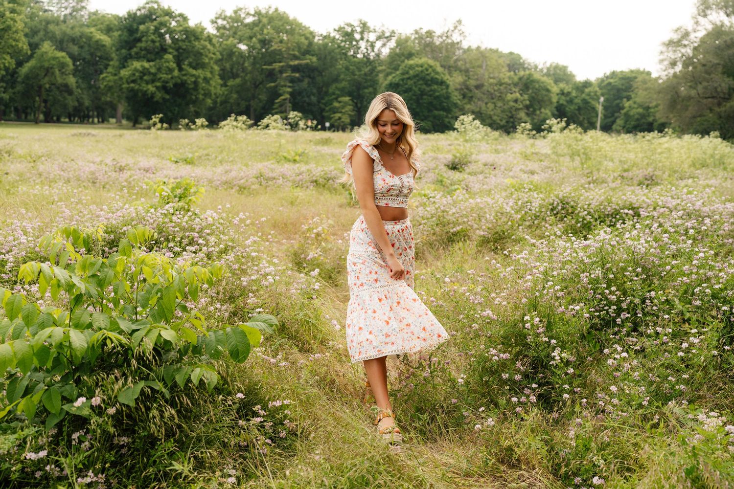 Summer fashion shot of floral dress worn in a wildflower meadow at golden hour.