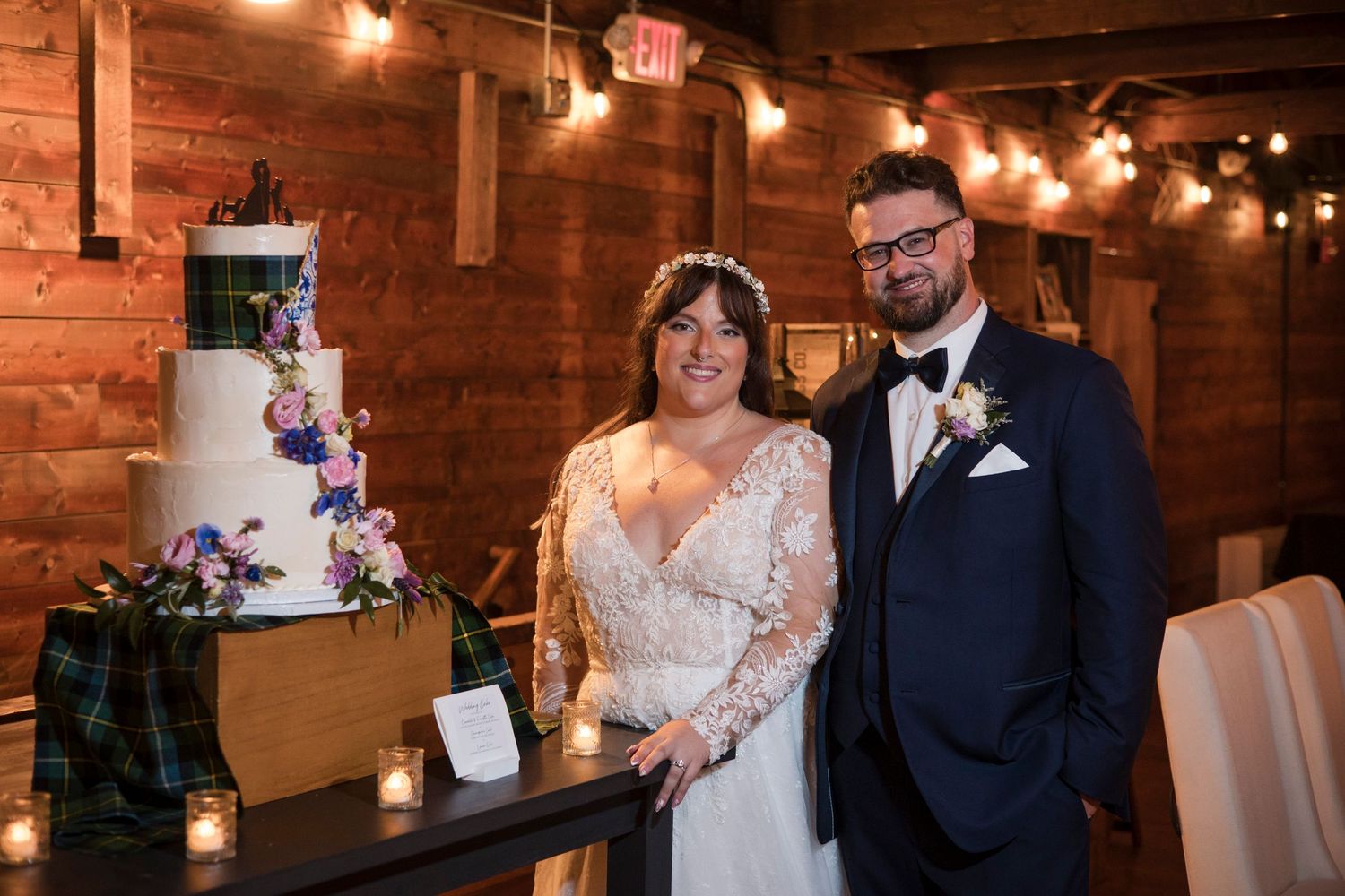 Rustic barn wedding celebration with warm lighting and exposed wooden beams with decorative string lights.