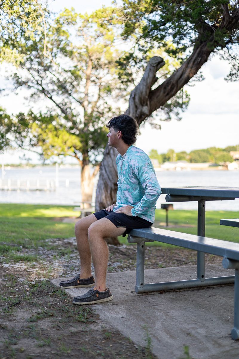 Park bench overlooking waterfront with green trees and grass along shoreline.