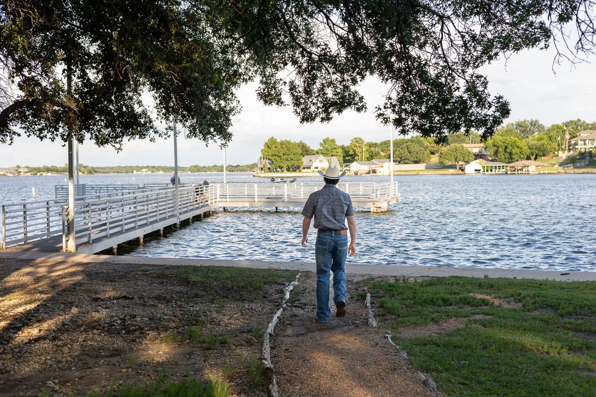 Five connected photos show a scenic waterfront boardwalk with wooden railings along a calm lake on a sunny day.