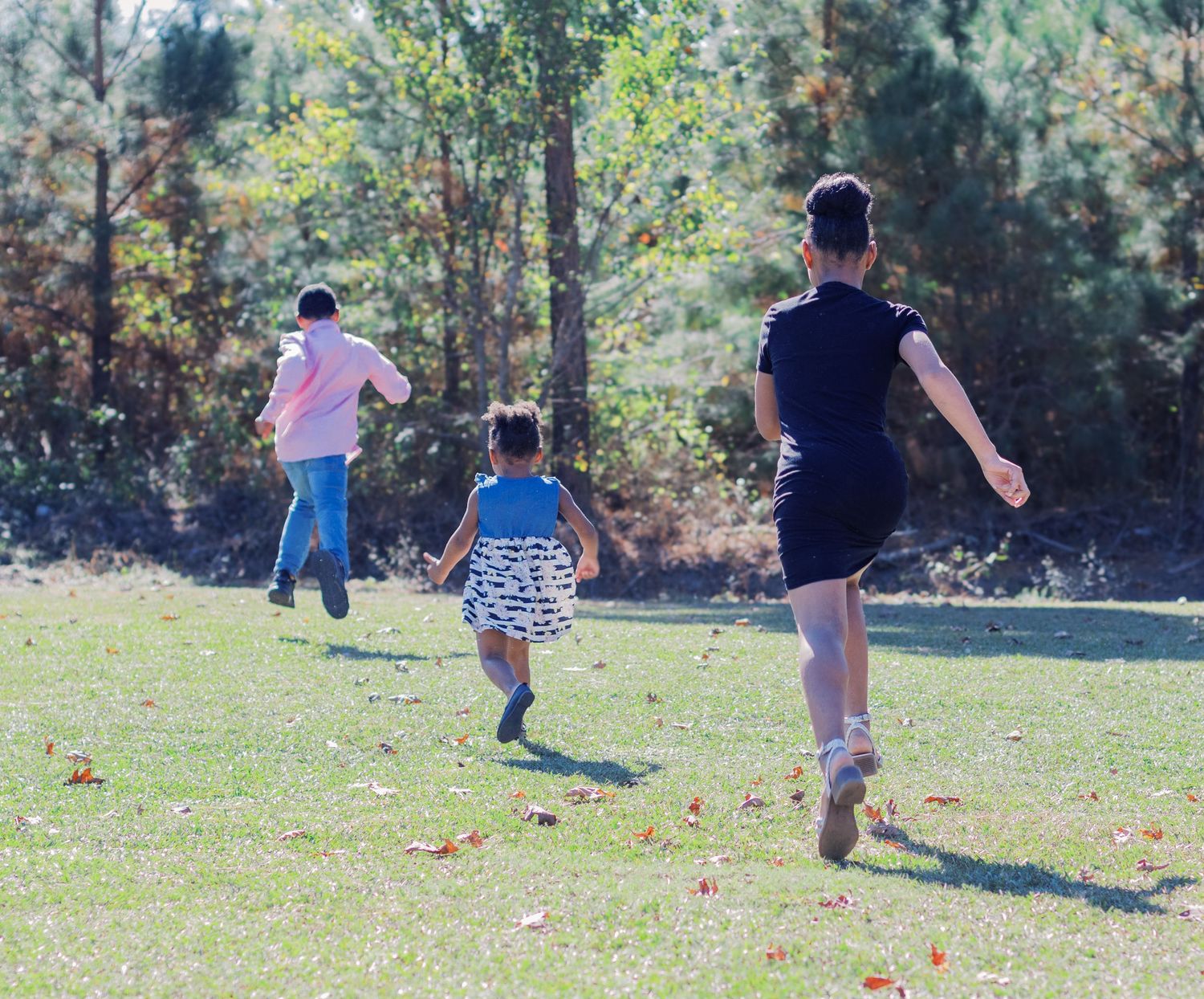 A family enjoying a sunny day together outdoors in casual attire on green grass.