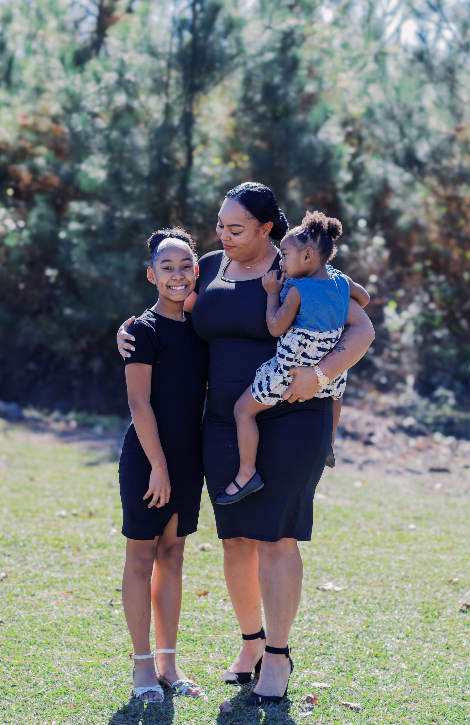 A family enjoying a sunny day together outdoors in casual attire on green grass.