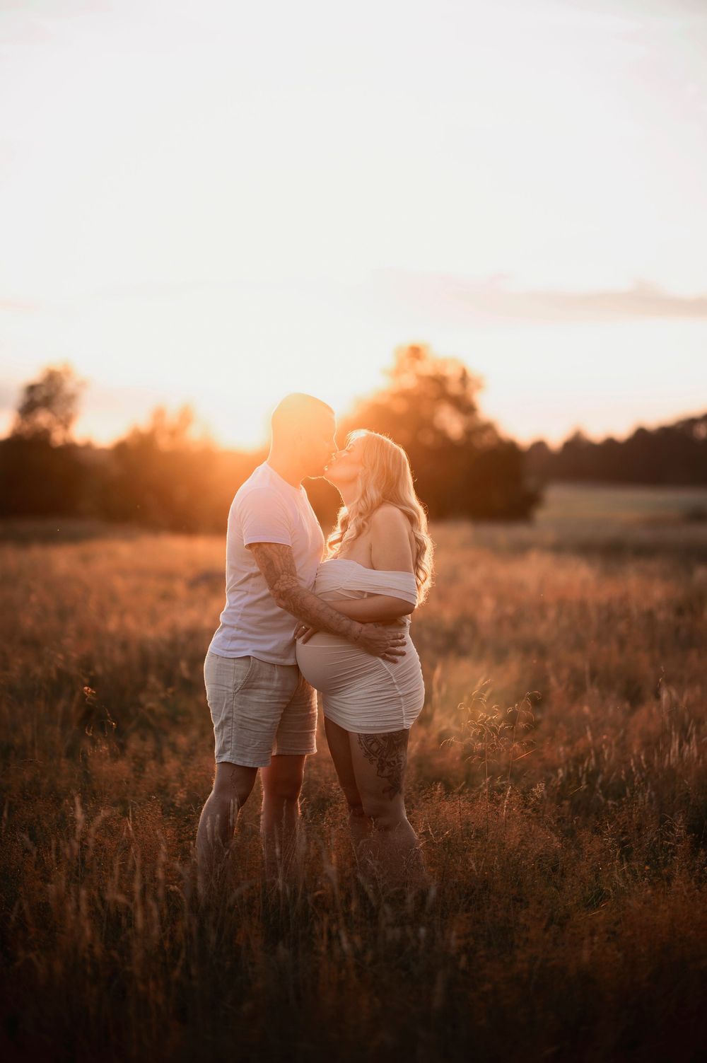 Parfotografering i solnedgång – två personer omfamnas i ett gyllene fält under en varm sommarsol. Perfekt idé för somriga, romantiska bilder