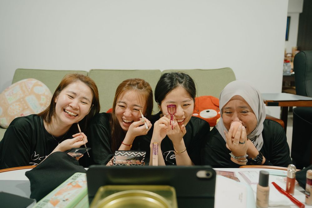 Four students sitting at a study table making playful poses while enjoying a study session together.