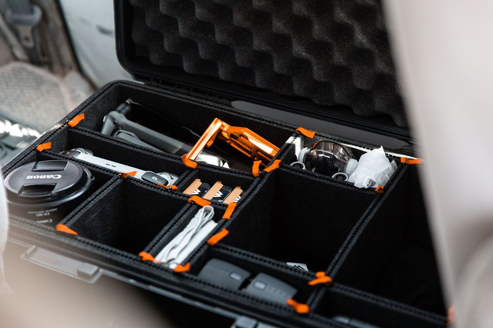 Inside view of a black protective case containing camera equipment with orange foam dividers and metal components.