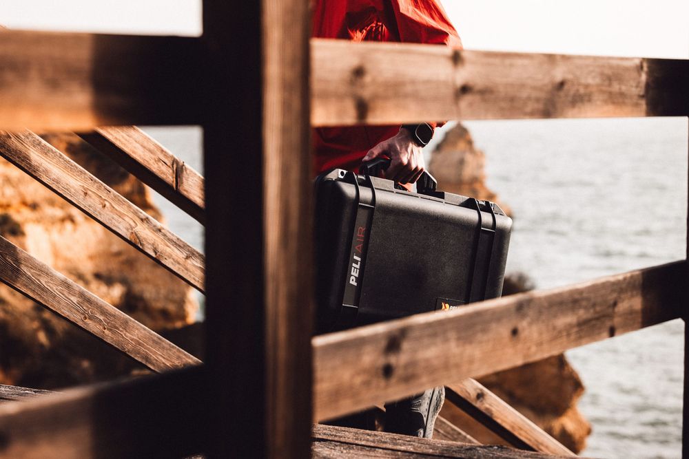 A black camera case sits on rustic wooden planks during golden hour lighting.