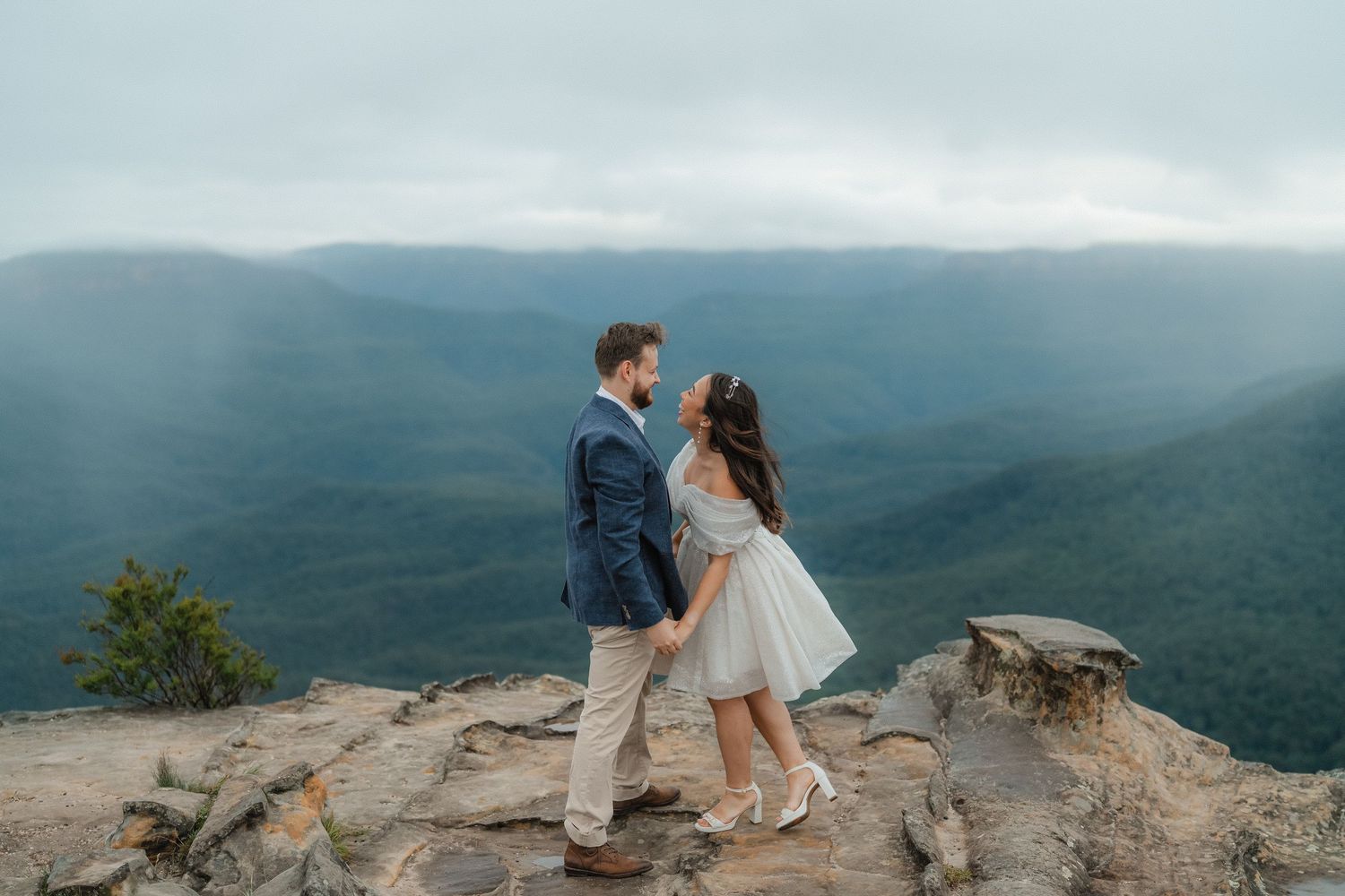 Romantic mountain top moment with sweeping valley views and cloudy skies at sunset.