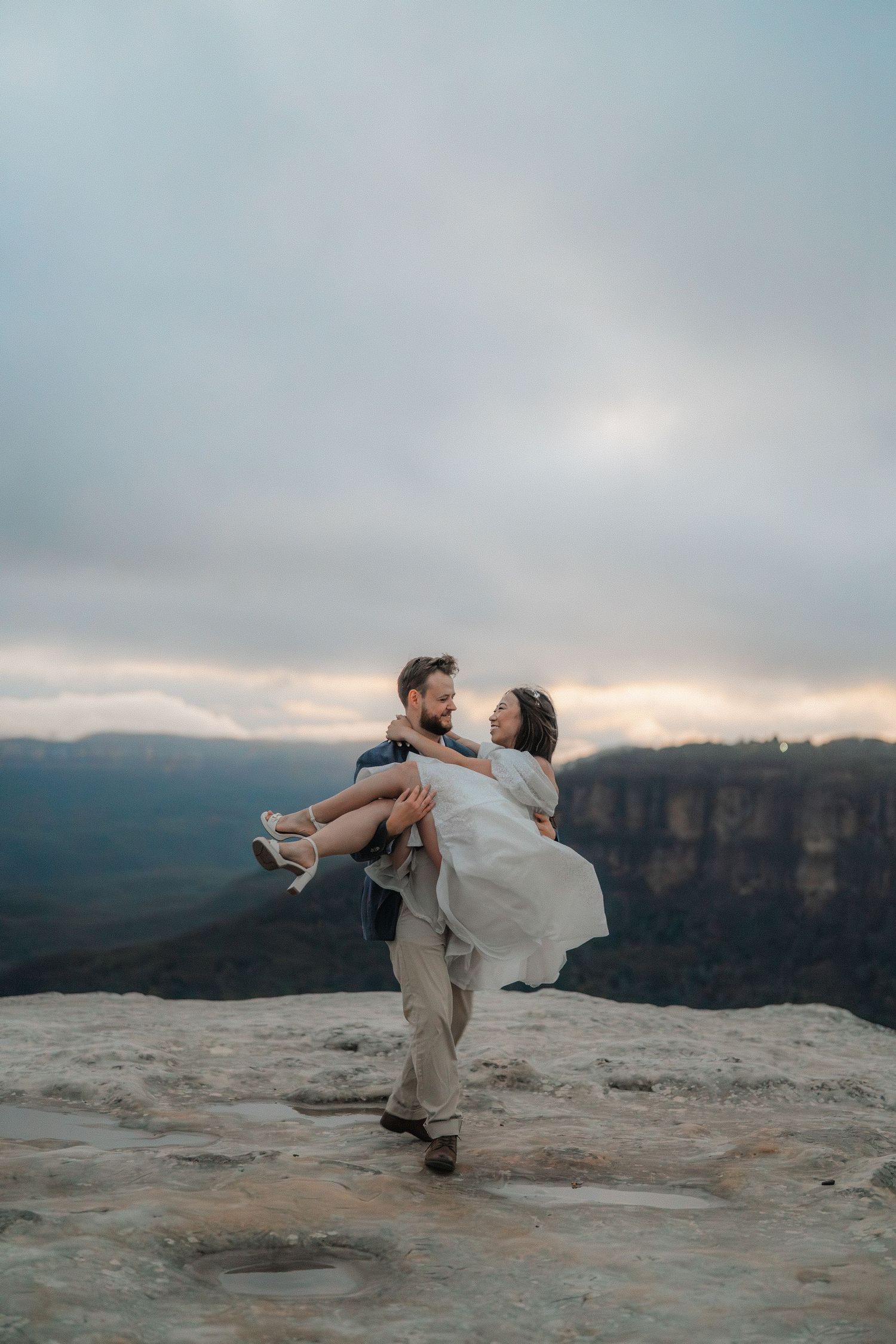 A romantic lift pose captured on a scenic mountain overlook during golden hour.