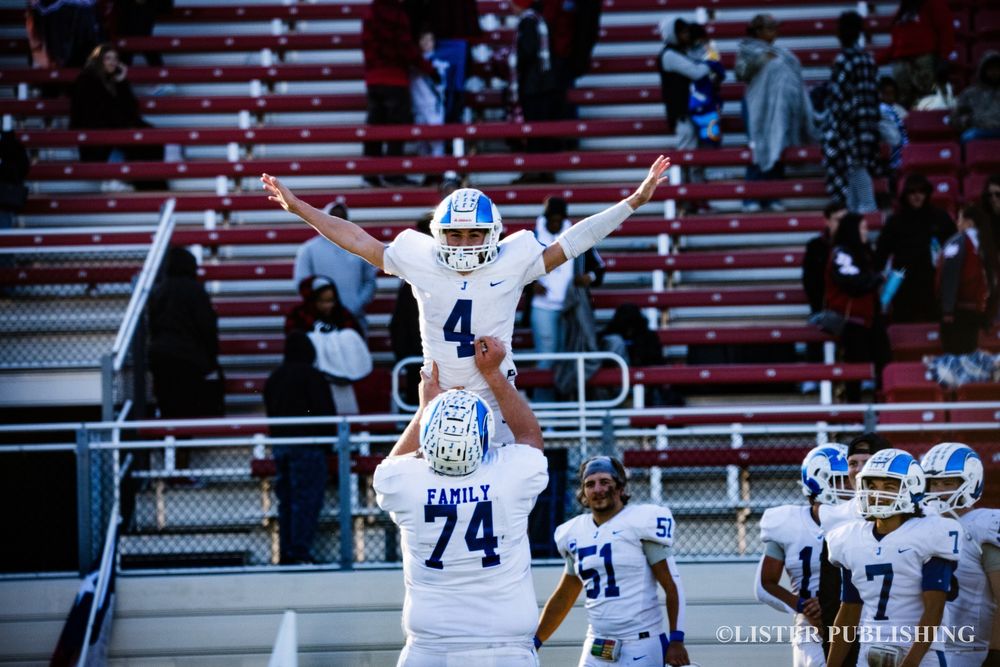 Football player celebrates victory being lifted by teammate on field.