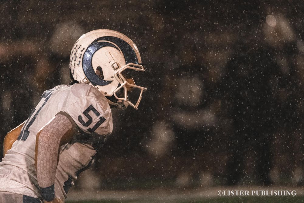 Close-up profile shot of football player in white uniform and helmet.