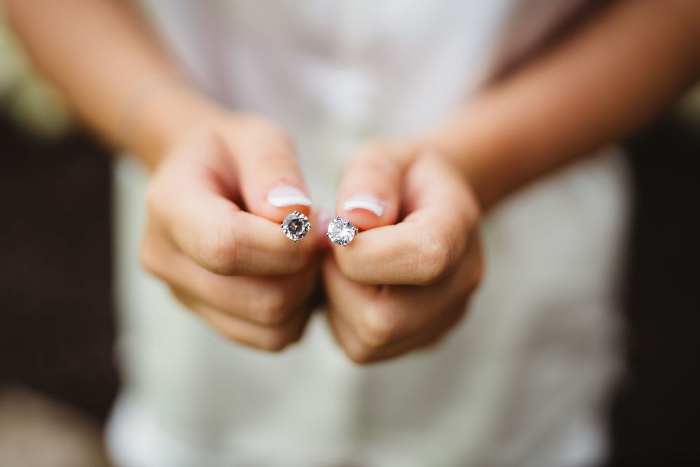 Close-up shot of hands holding a wedding ring with delicate detail in soft focus.