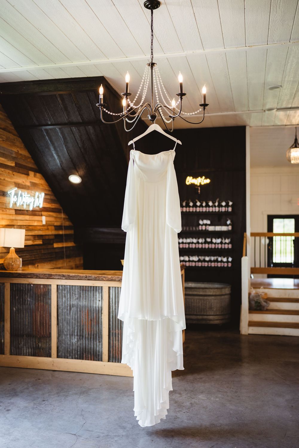 Empty rustic wedding venue interior with white curtains and chandeliers.