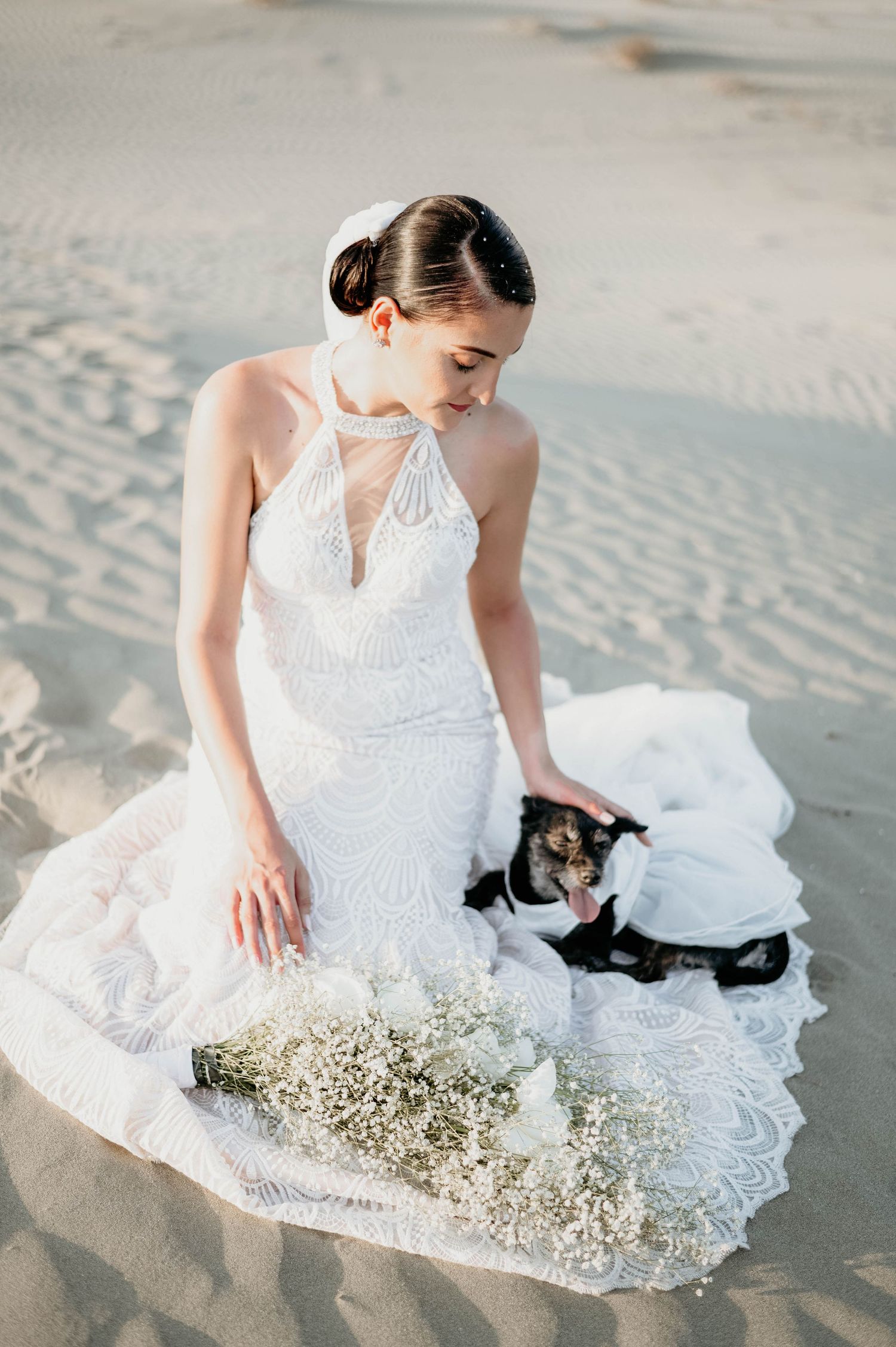 White lace gown flowing across sandy beach during seaside bridal photoshoot at sunset.