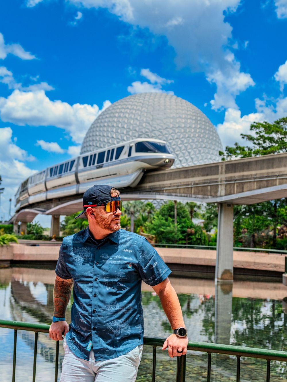 Person in blue shirt near monorail track with Epcot sphere visible in background at Disney World.