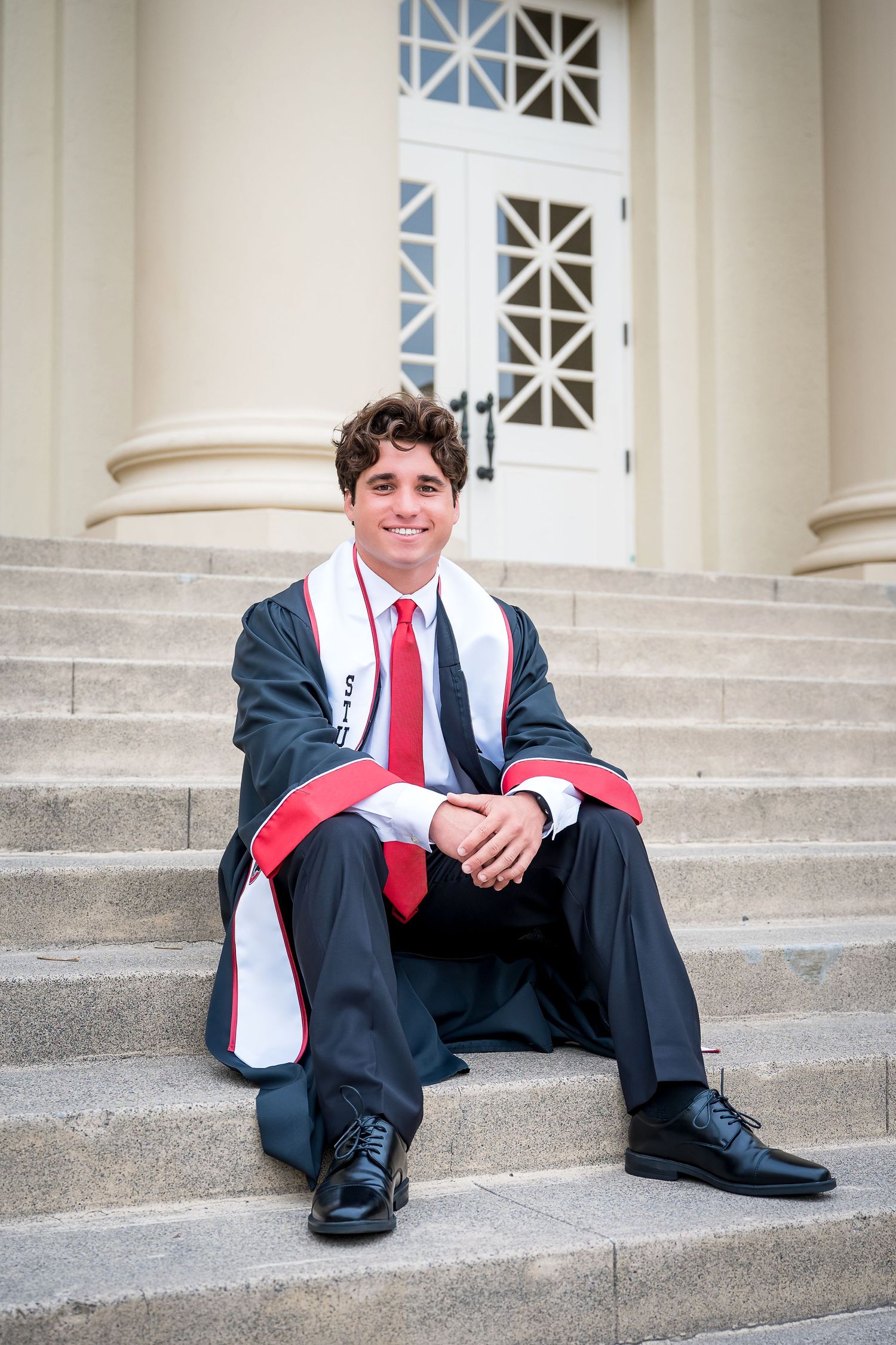 Twin graduates standing side by side in front of Memorial Hall at Chapman University