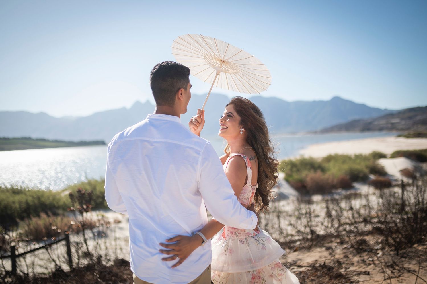 A tender romantic moment between a couple sitting in soft misty light outdoors.