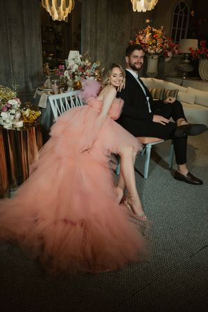 Flowing coral tulle ballgown movement captured during an indoor celebration under chandeliers.