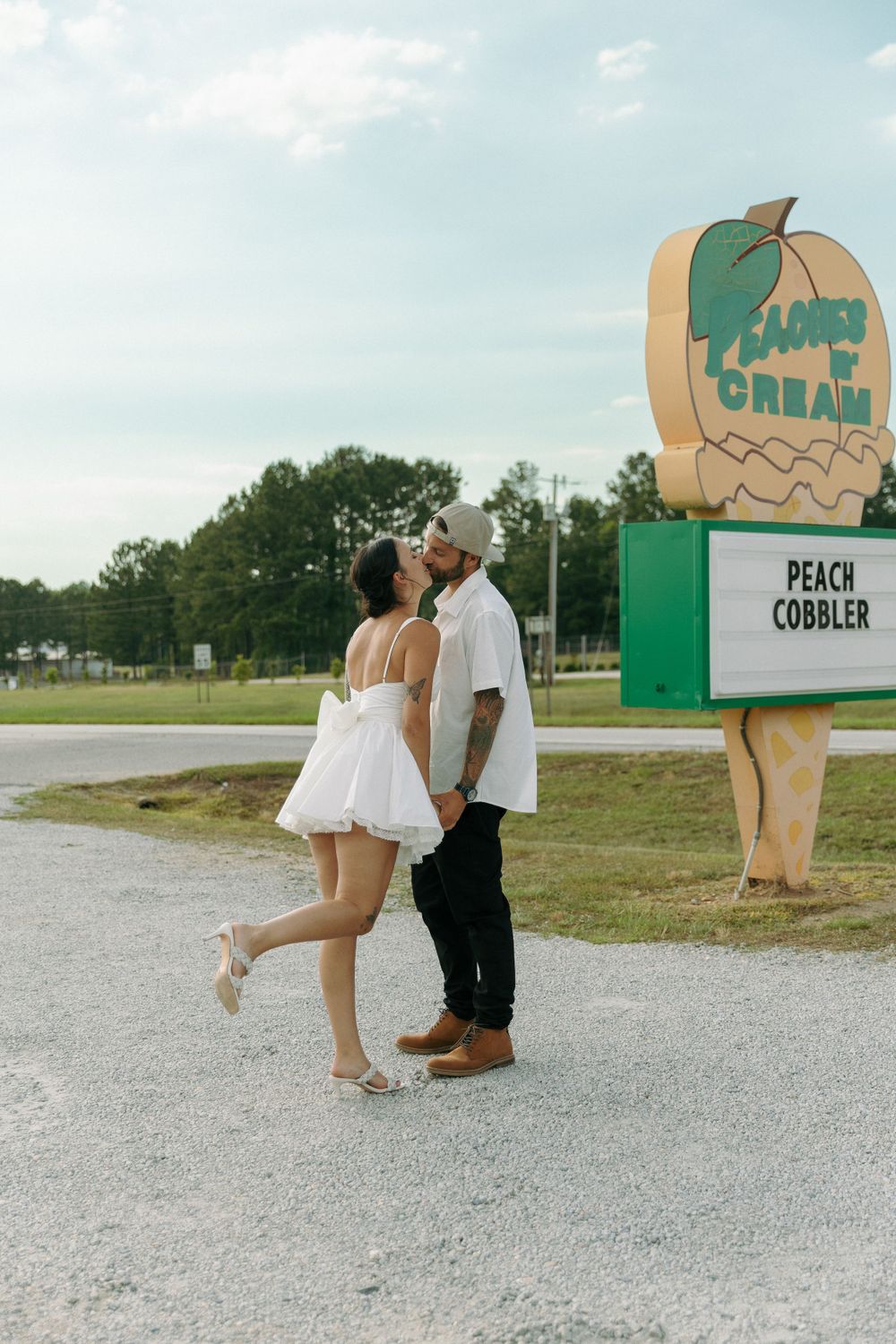 A couple sharing a romantic moment outside a vintage ice cream shop with 'Peach Cobbler' sign in the background.