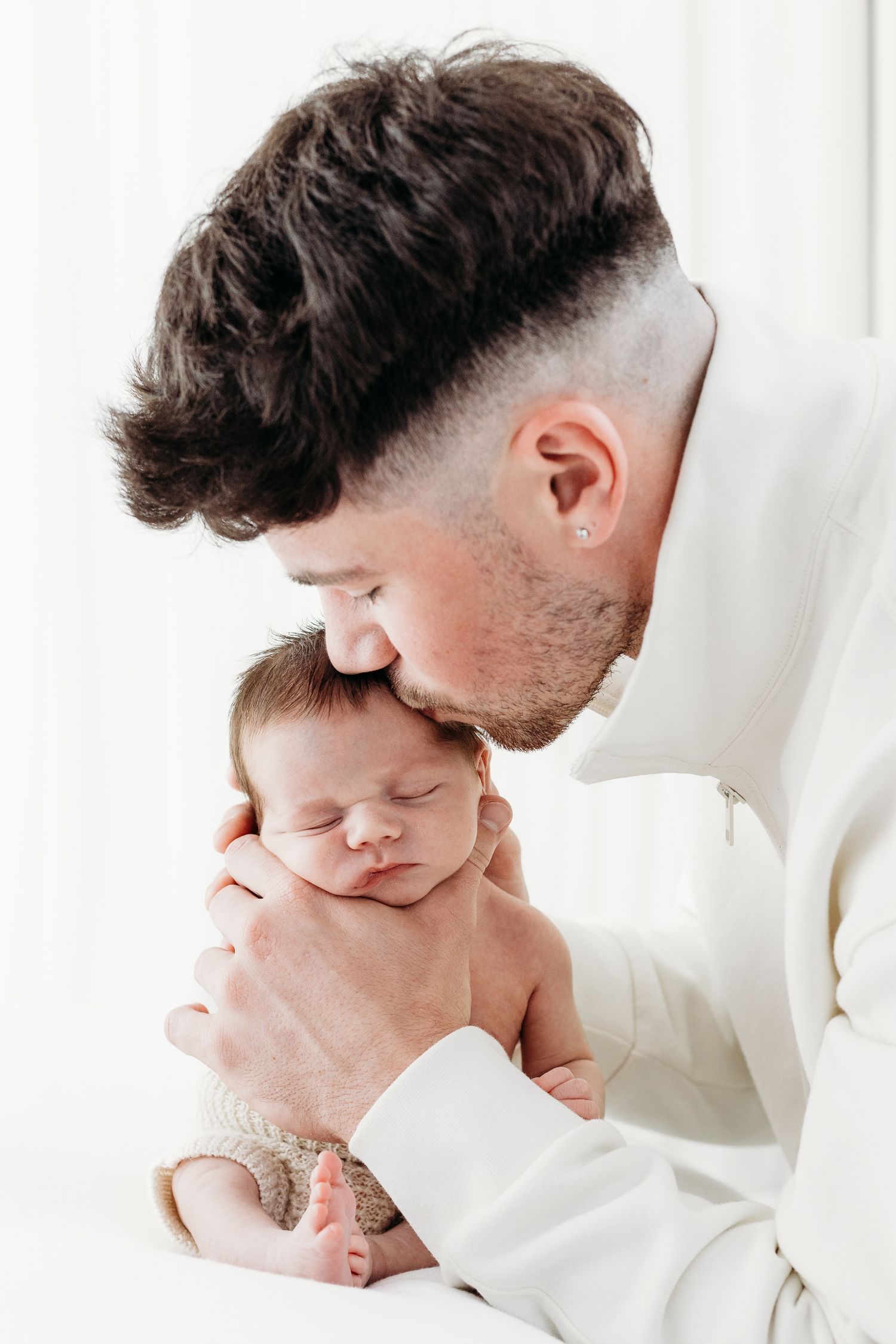 Father cradling tiny newborn baby during family photoshoot at Mapperley photography studio in Nottingham, tender moment captured.