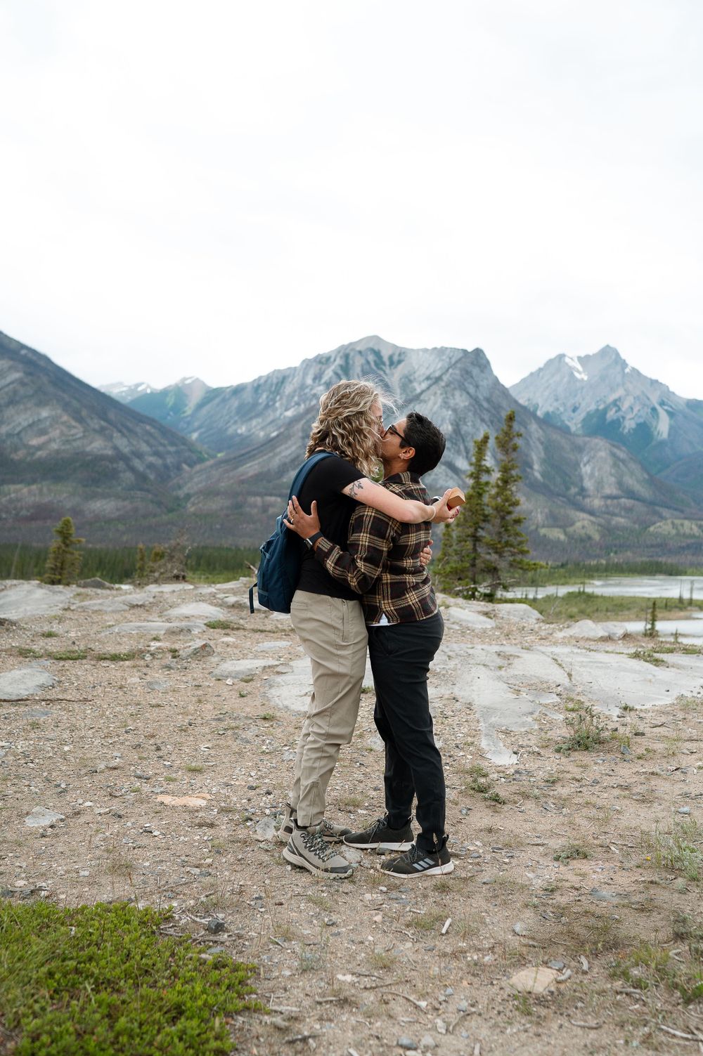 Couple sharing intimate moment with Canadian Rockies as dramatic backdrop.