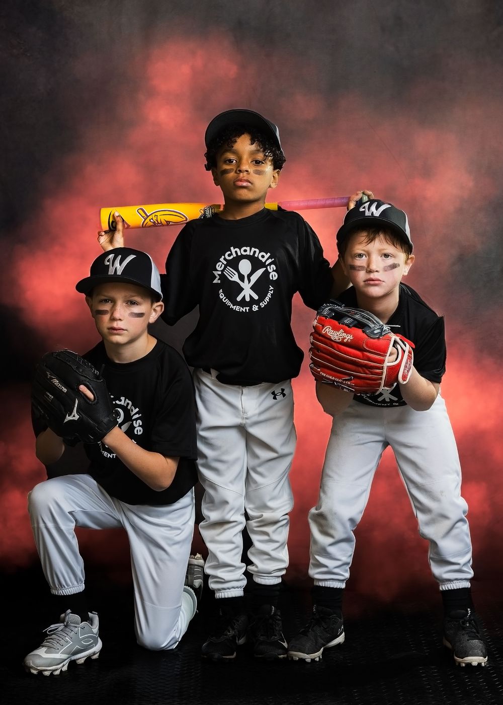 Three young baseball players in matching uniforms pose dramatically against a bold red and black background.