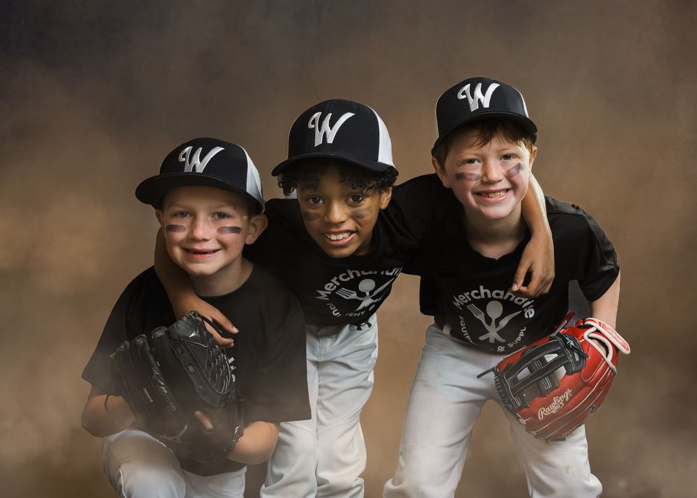 Three smiling young baseball players in W caps and Merchandise jerseys pose together in a studio portrait.
