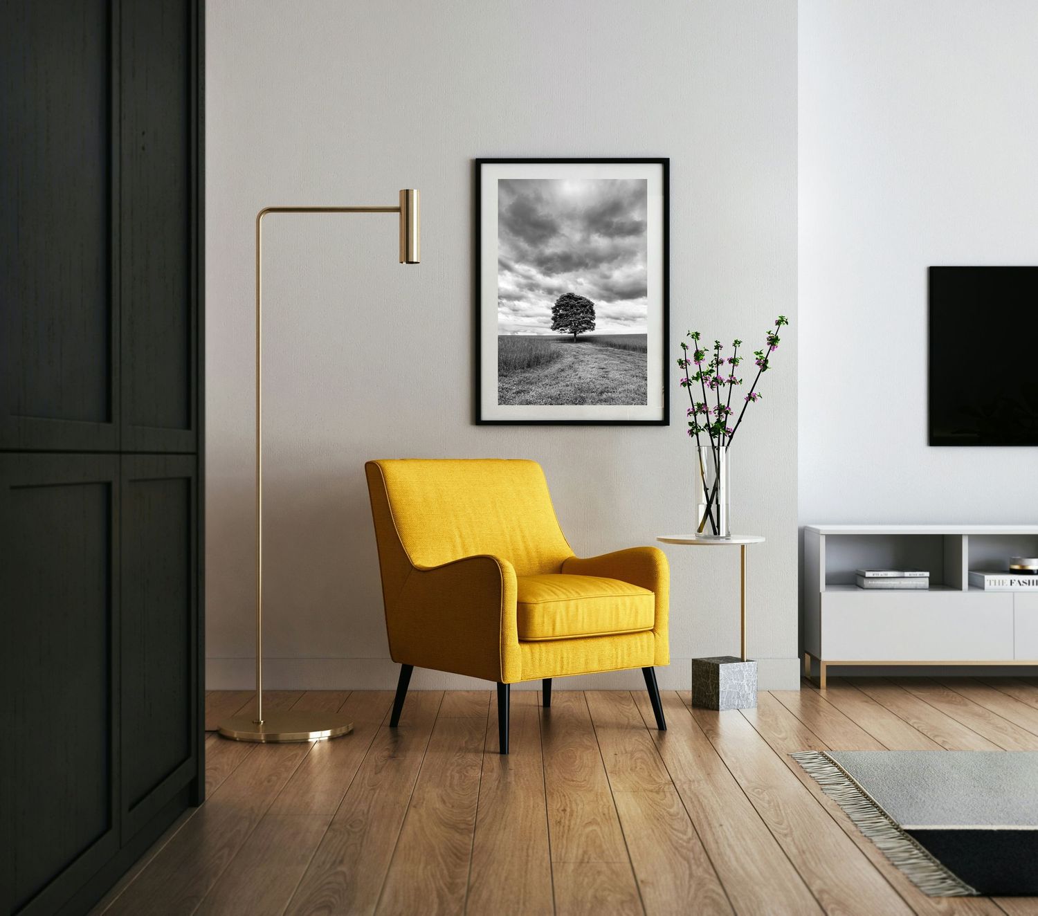 A yellow chair with a black and white fine art print on the wall behind it. The print is a lone tree in a field with a stormy sky overhead.