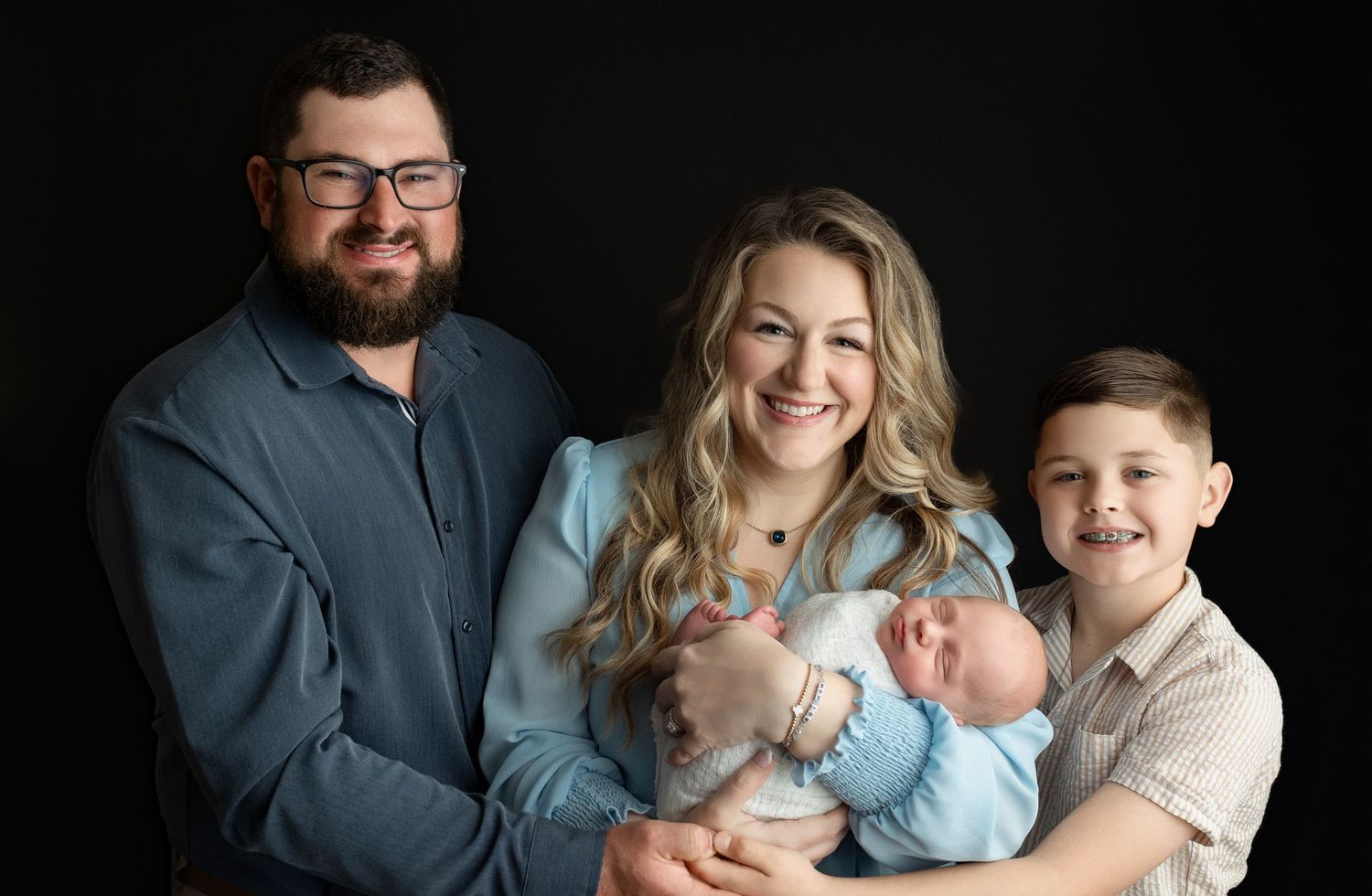 A proud family, all smiling at the camera, holding the newborn baby boy. Greenville SC newborn photographer, Easley SC newborn photographer
