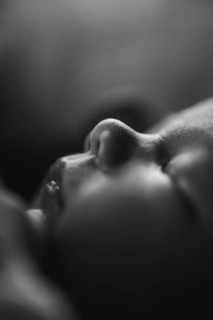 Close up artistic black and white profile portrait of a sleeping figure with soft lighting and shallow depth of field.