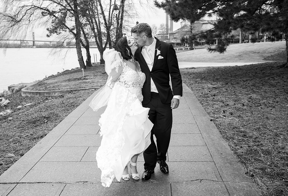 Black and white portrait of wedding couple walking along outdoor pathway.
