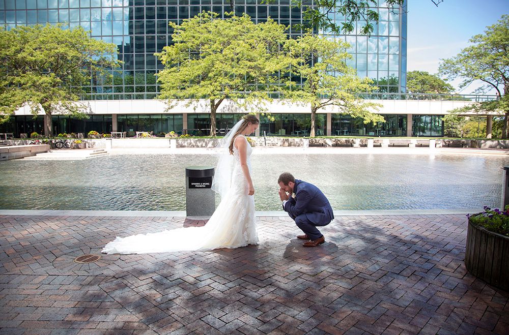 Playful wedding photo shoot near modern building with reflective pool.