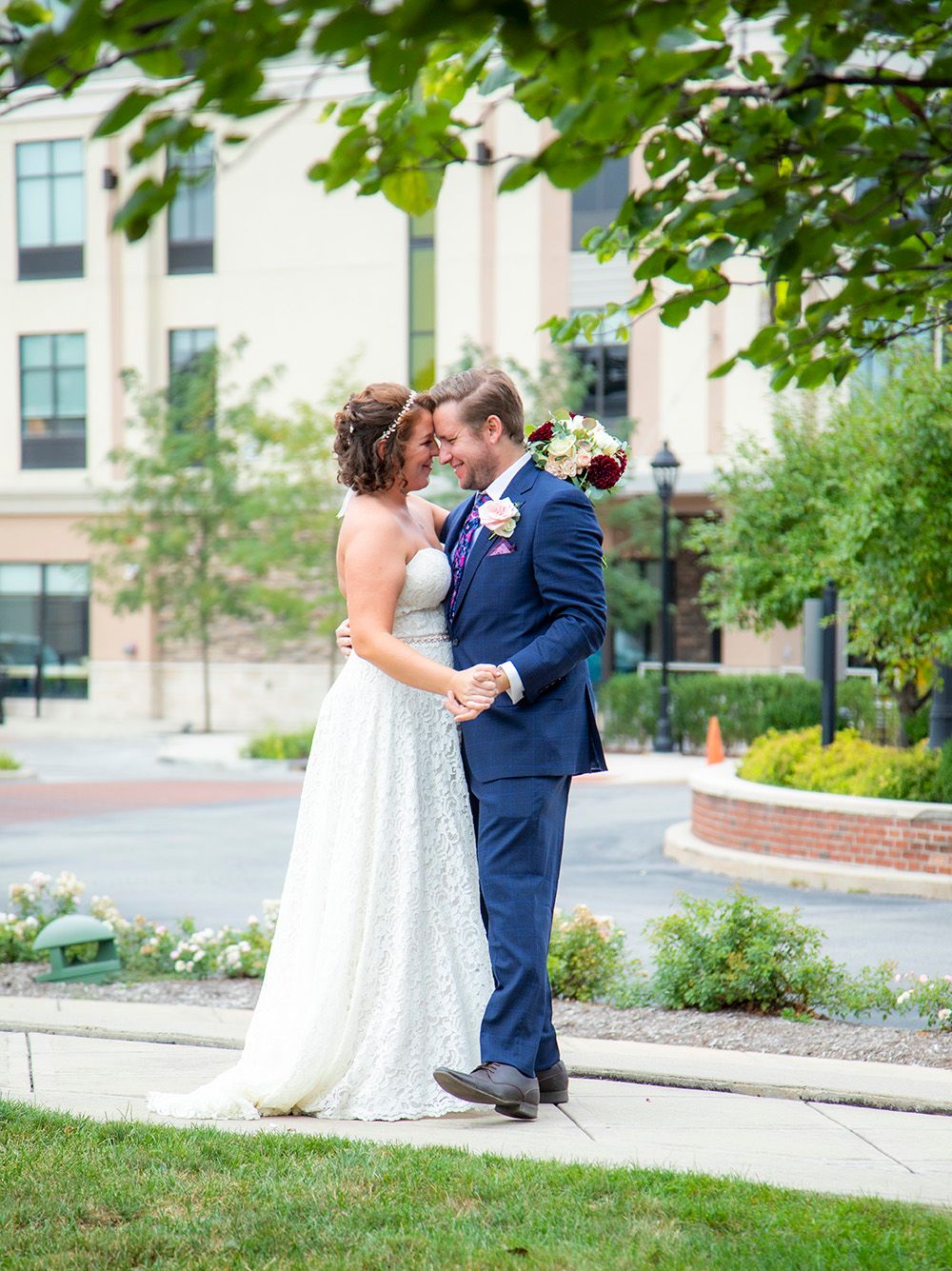 Elegant couple sharing their first dance in formal wedding attire outside urban building.