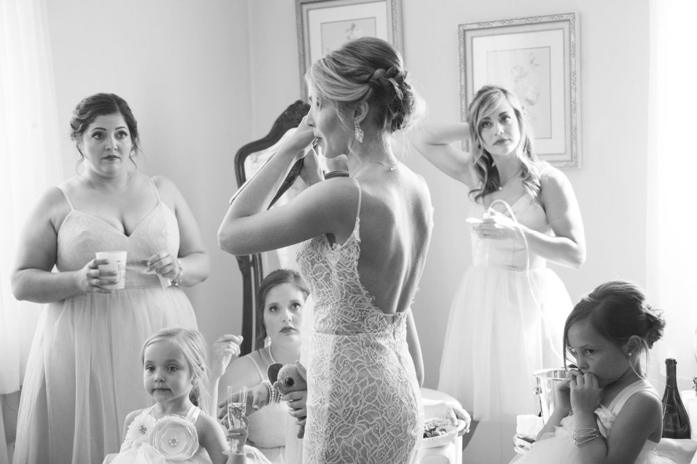 Candid getting ready moment captured in bright interior room with wedding preparations.