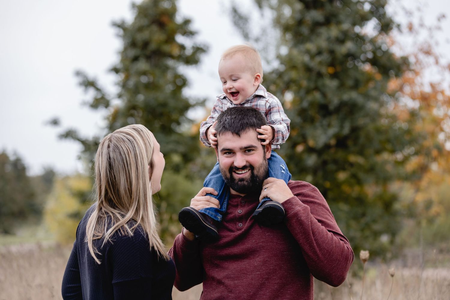 A joyful family moment outdoors with evergreen trees in the background during autumn.