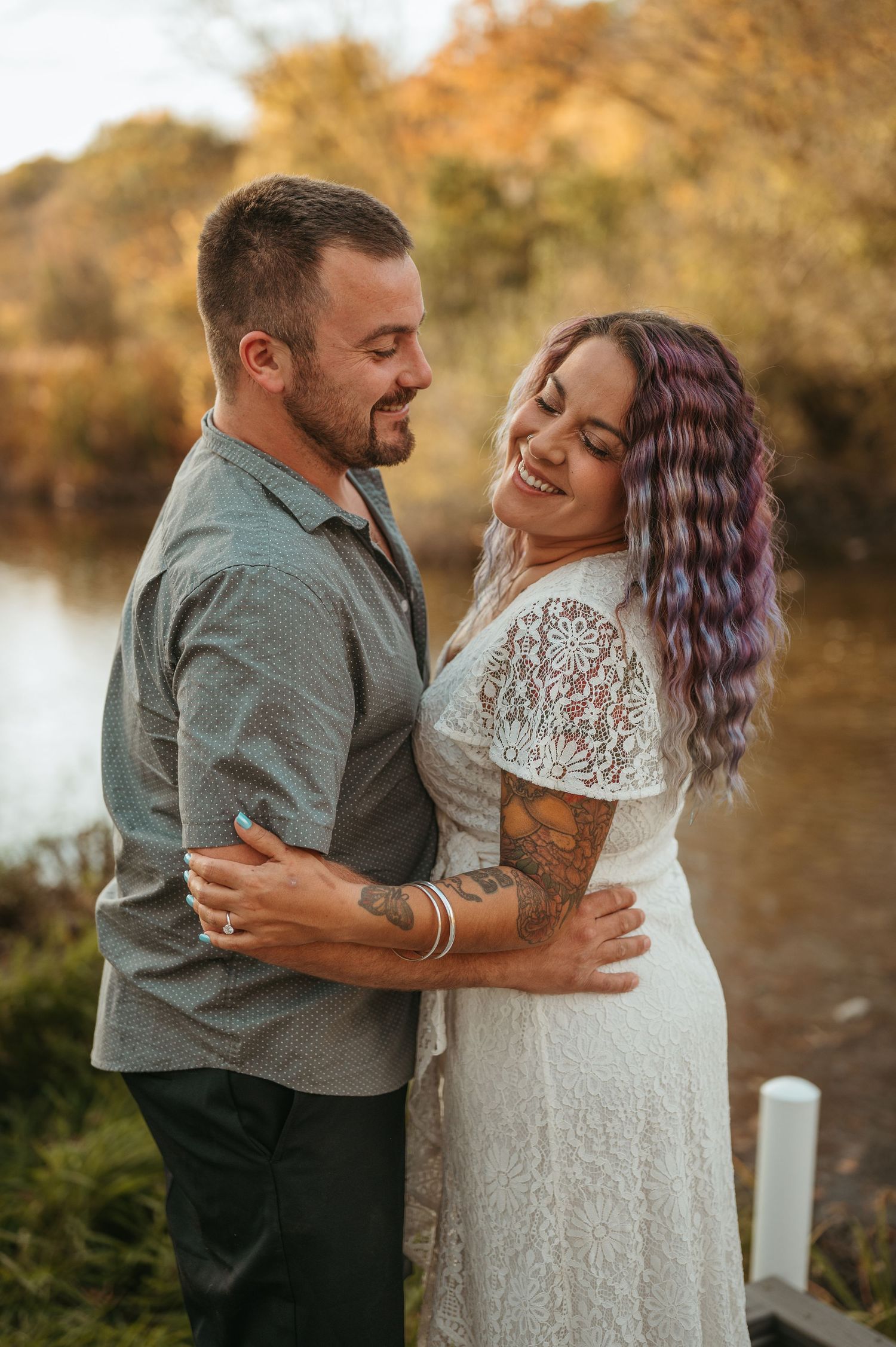 Couple embraces during an autumn outdoor photoshoot wearing white and casual attire.