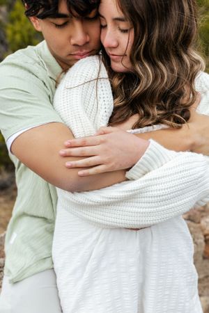 A couple embraces tenderly while wearing white and mint green in an outdoor portrait session.