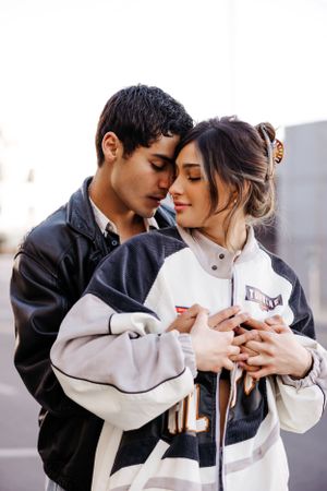 An intimate moment between a couple wearing matching black and white jackets as they embrace on an urban street.