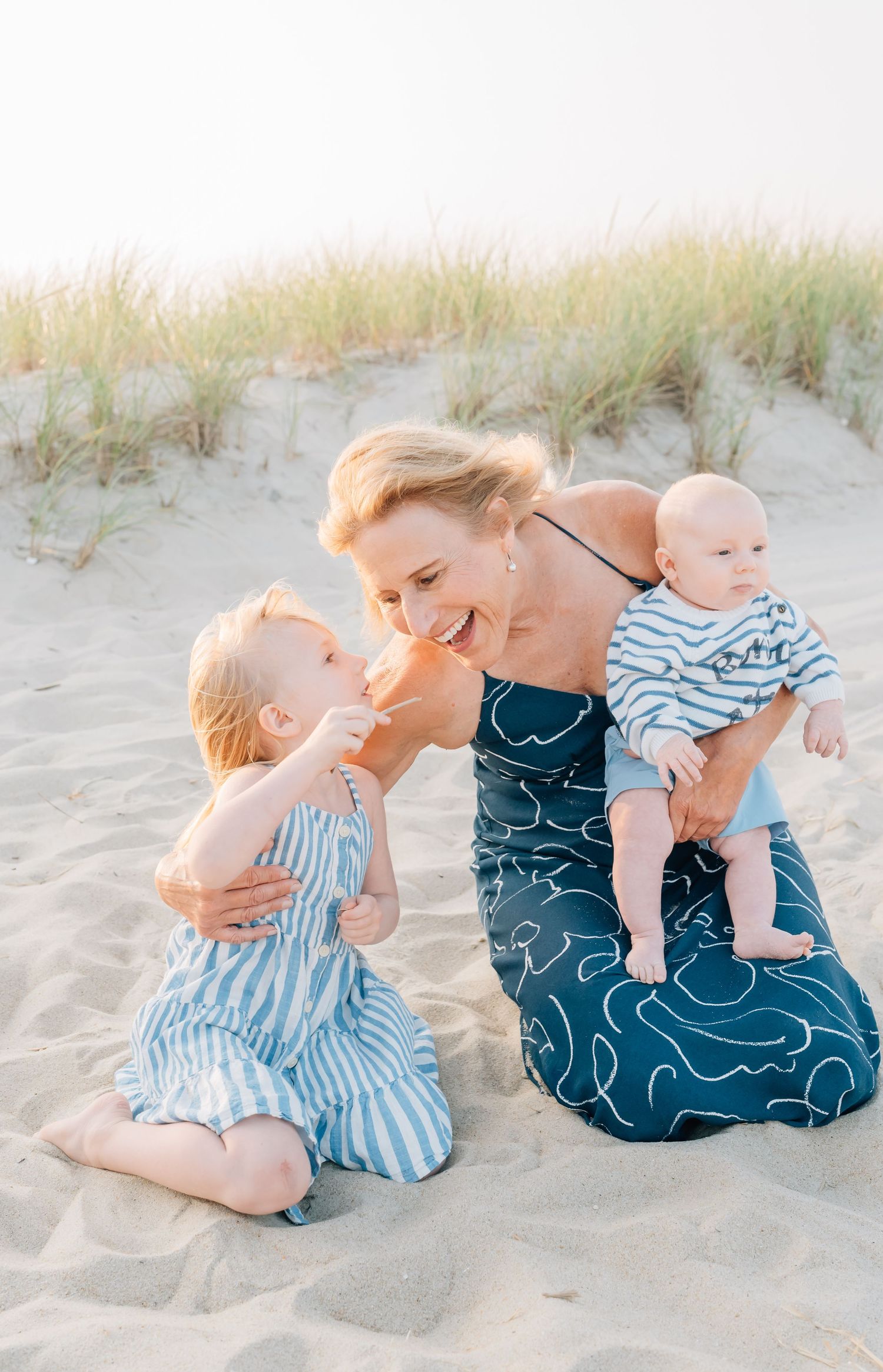 A grandmother hugs her granddaughter while also holding her grandson on the beach in Monmouth County nj.