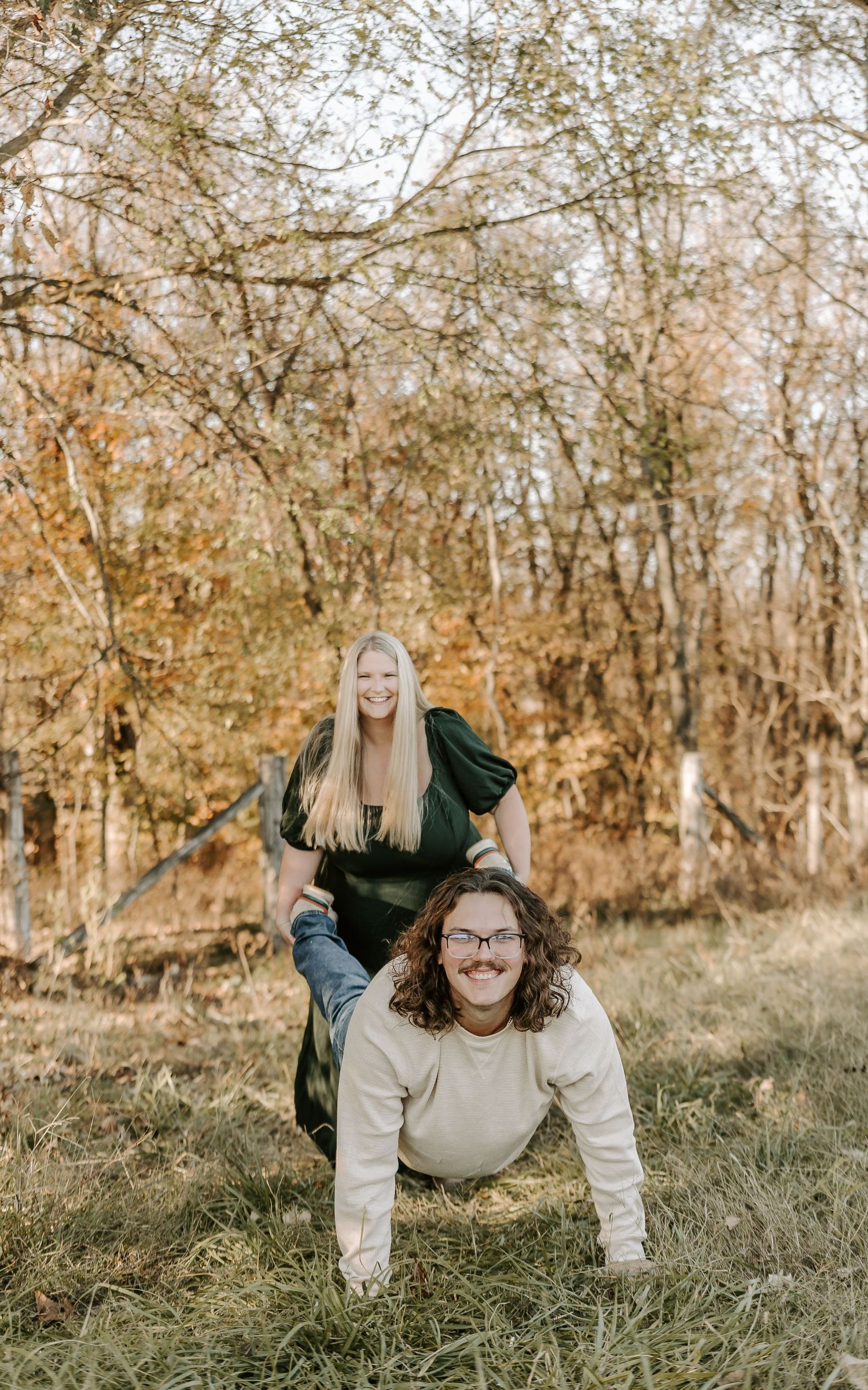 Playful couple doing push-ups together in autumn woods.