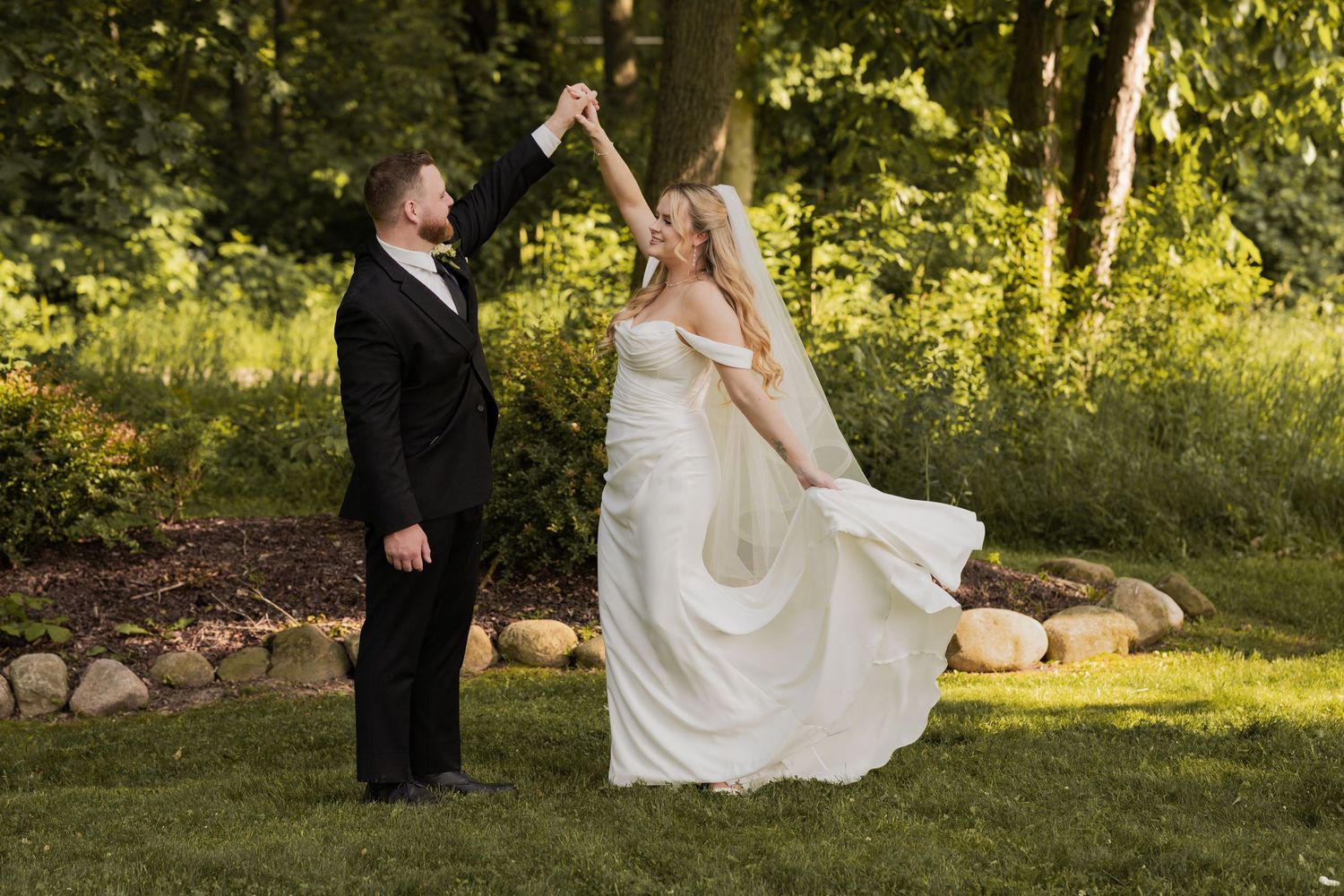 Wedding day and the groom is spinning the bride. They are smiling at each other.