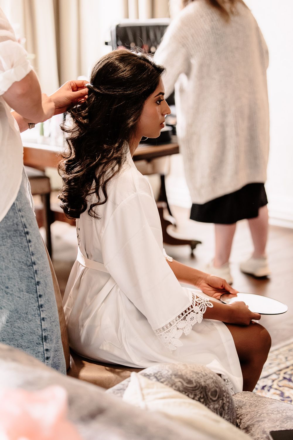 Getting ready scene with wedding dress preparations in soft natural light.