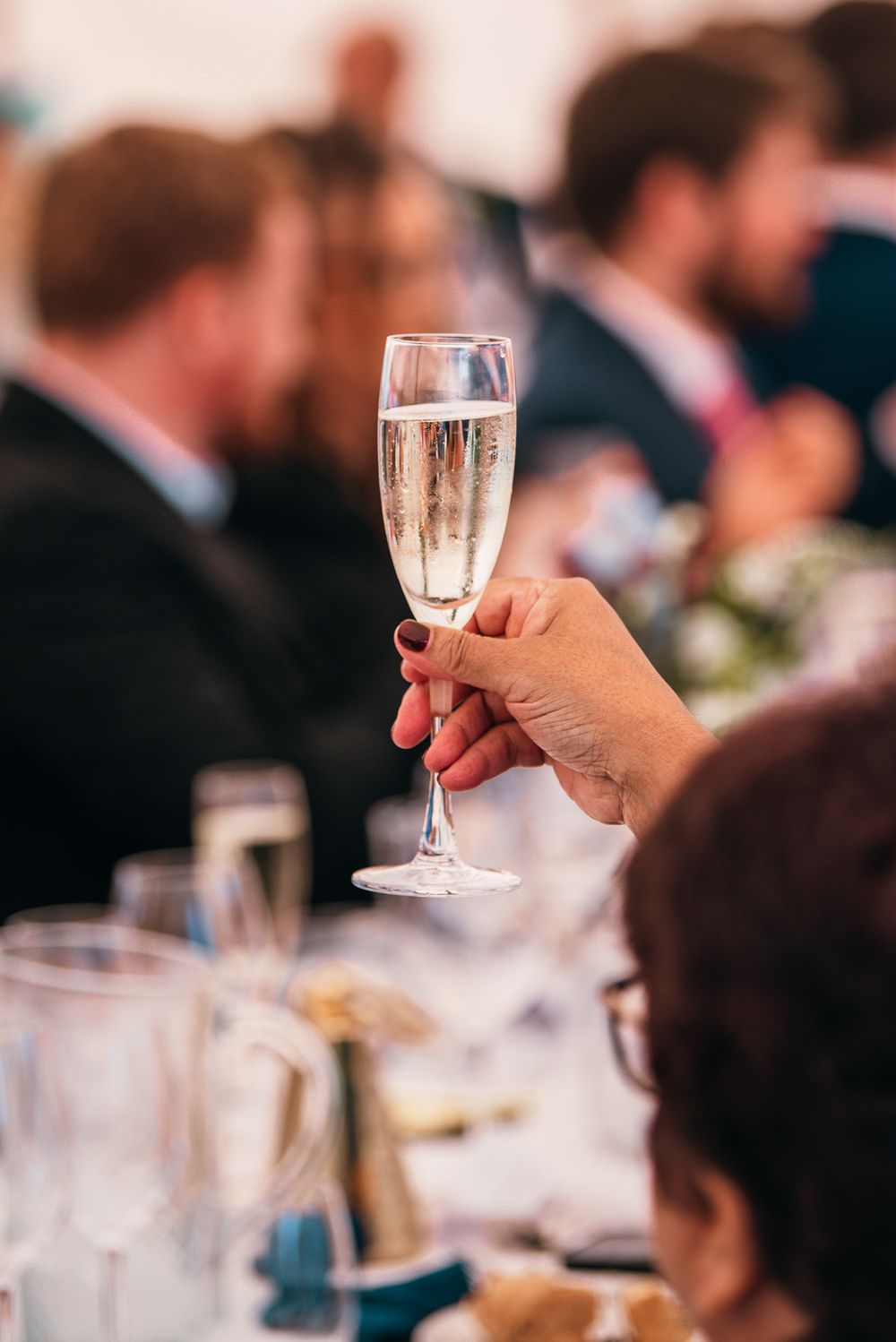 Champagne glasses being raised during wedding toasts at an elegant reception.