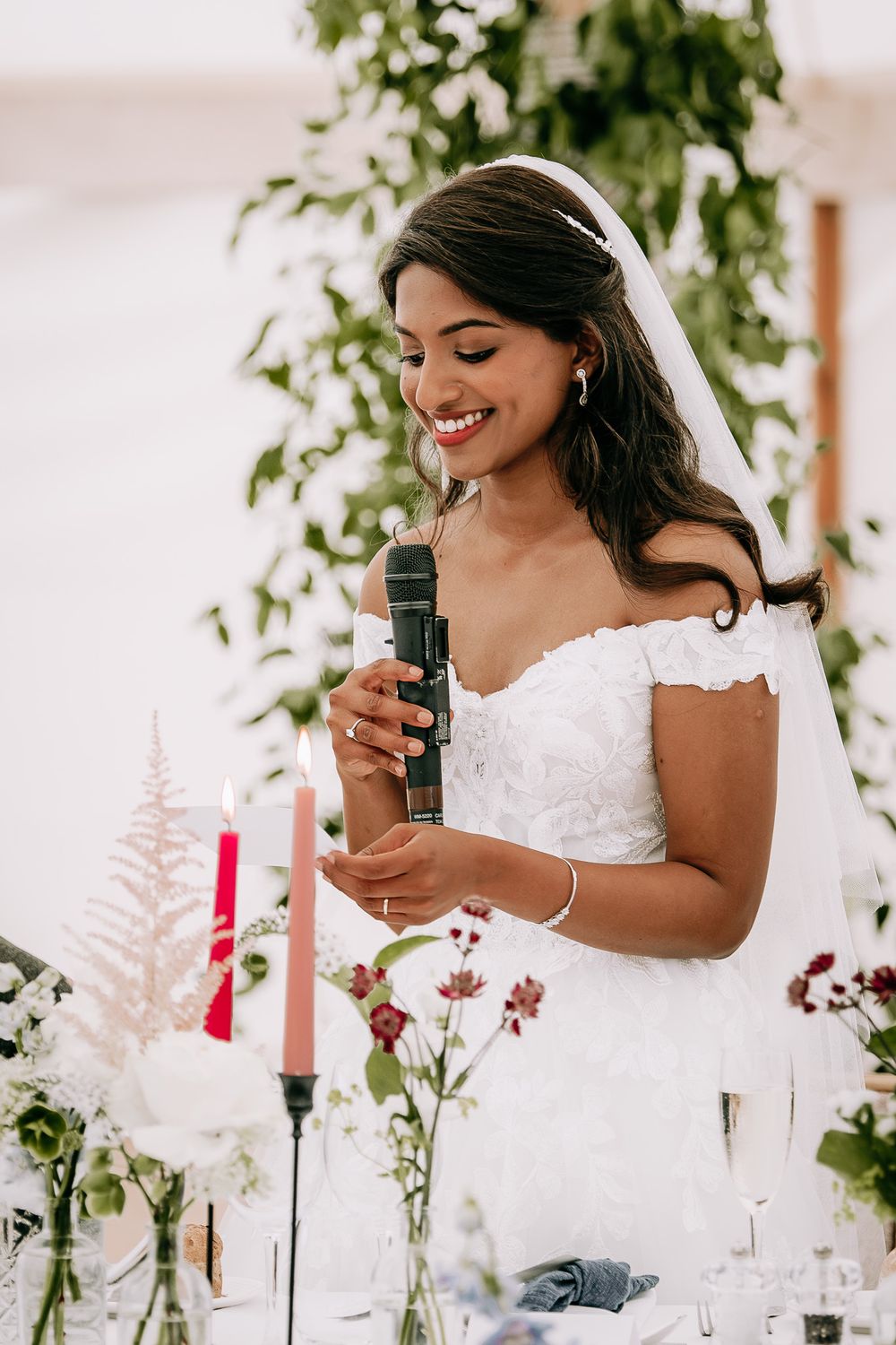 Close up of white wedding dress details with floral decorations and candles on table.